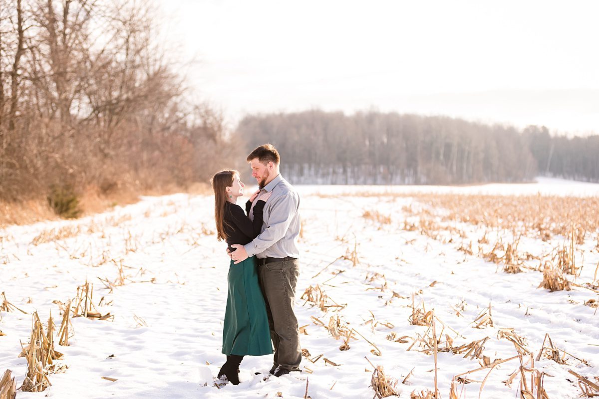Couple during sunset in cornfield during winter engagement photos near Charleston Lake, ON