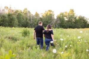 couple walking in field for their late summer engagement photos in Ottawa, ON