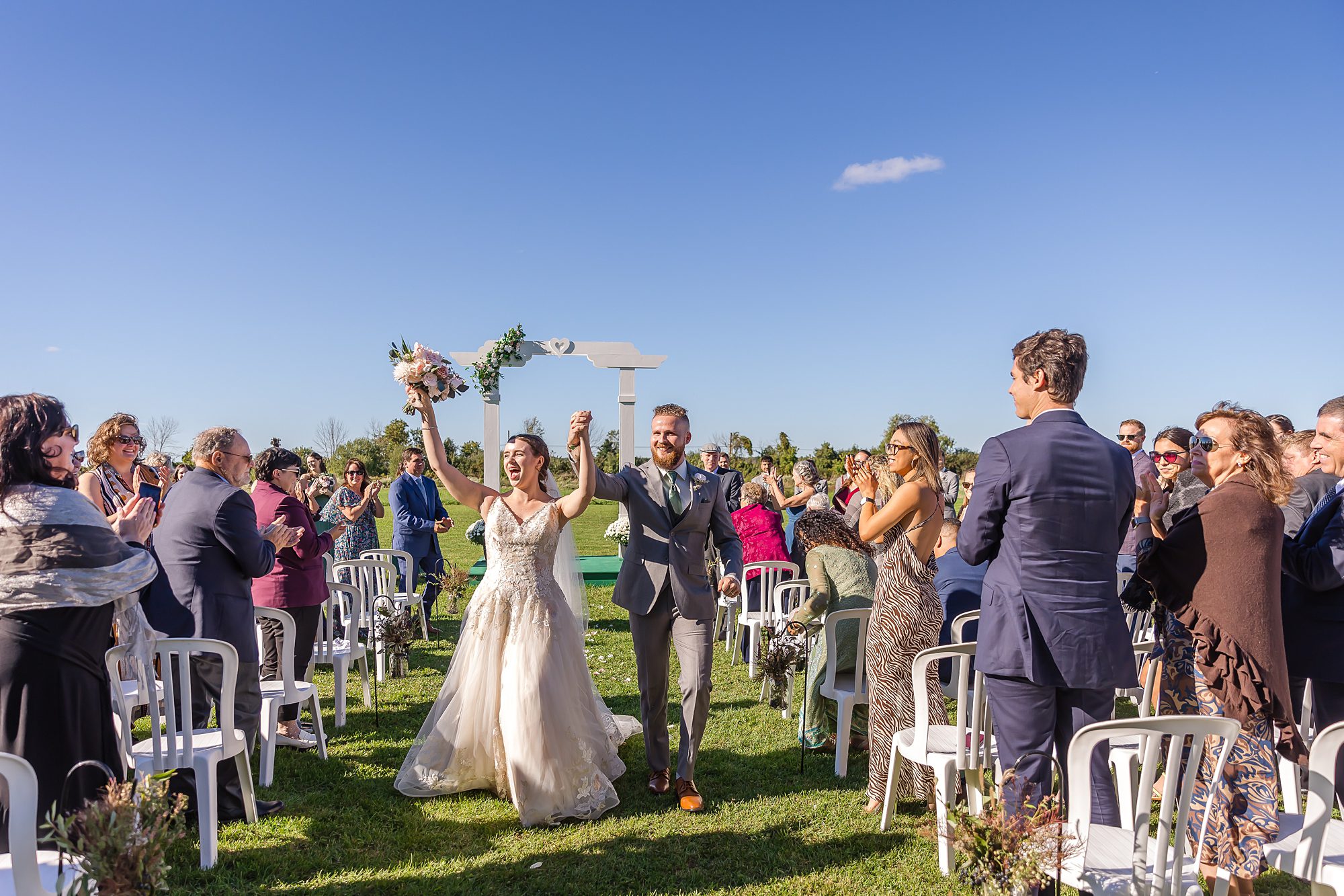 newlyweds celebrate walking down the aisle during outdoor ceremony