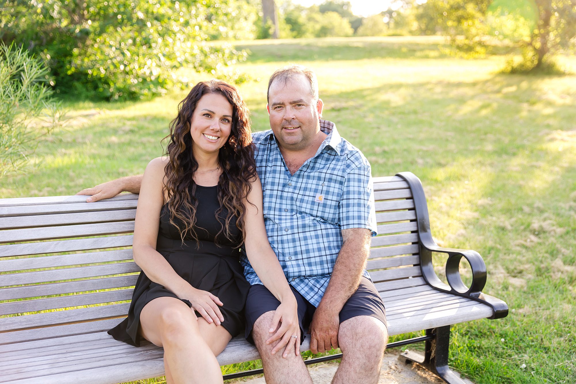 couple sitting on park bench during engagement photo